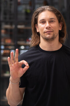 30s caucasian man in casual clothes, smiling with a ok or okay hand gesture for acceptance