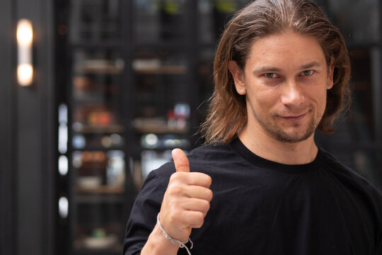 30s caucasian man in casual clothing giving a thumbs up with a happy satisfied smile