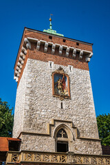 A detailed low-angle perspective captures the grandeur of St. Florian's Gate tower, showcasing its brick, stone, and fresco in Krakow, Poland. © Danica Chang