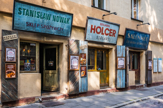 Krakow, Poland - Jul 18, 2025: Old shops featuring hand-painted business signs, rustic wooden doors, and posters for live music, creating a nostalgic scene in Kazimierz, Krakow, Poland.