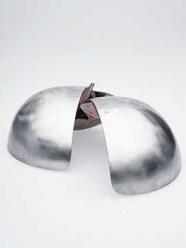 Domed steel shoulder cops with leather attachment points displayed against a bright background, emphasizing clean curved metal surfaces.