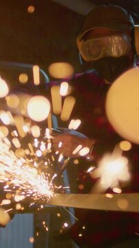 Welder at work in industry, cutting - slow motion. Lots of sparks in factory. Man cuts metal with a angle grinder. Male at a construction site cuts off a piece of metal, fiery sparks and particles fly