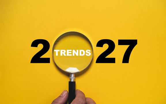 2027 trends concept with magnifying glass highlighting emerging trends on a bright yellow background symbolizing future forecasting of market research and business innovation to strategic planning.
