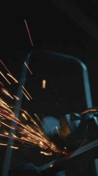 Male industrial or construction worker cuts metal with a angle grinder. Man uses circular saw at garage or workplace. Cutting raw material with flying red sparks at the factory or plant. Slow motion