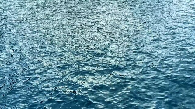 Calm blue ocean water with gentle ripples and small waves creating a textured, reflective surface ideal for backgrounds, nature projects, marine themes, travel imagery, relaxation and design,4K.