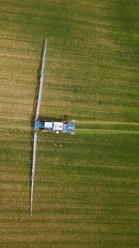 Blue crop sprayer with extended booms moving along parallel tracks