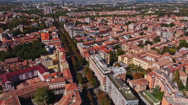Aerial drone view of Ferrara, Italy, showcasing the historic city center, terracotta rooftops, churches, medieval streets, green spaces, and the Emilia-Romagna cityscape.