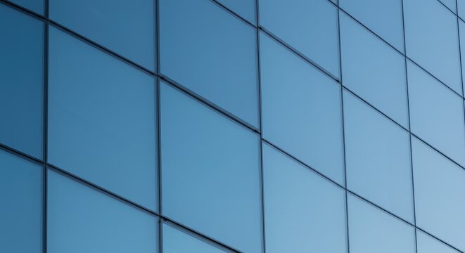 Modern glass office building exterior with clean geometric blue panel design under clear sky