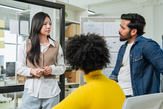 Serious multiethnic coworkers disagreeing during tense meeting in office with skeptical businessman frowning