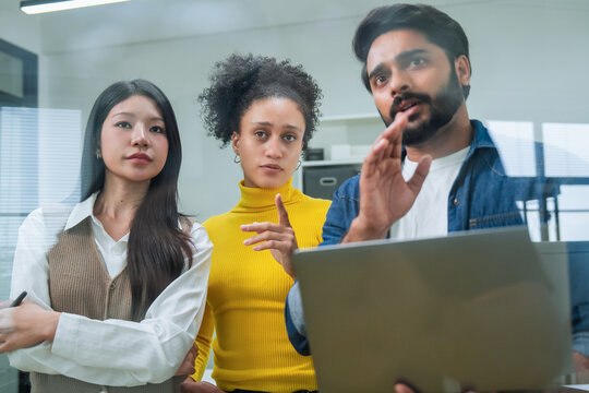 Skeptical businesswoman with crossed arms listening to colleague explaining idea during team meeting in office