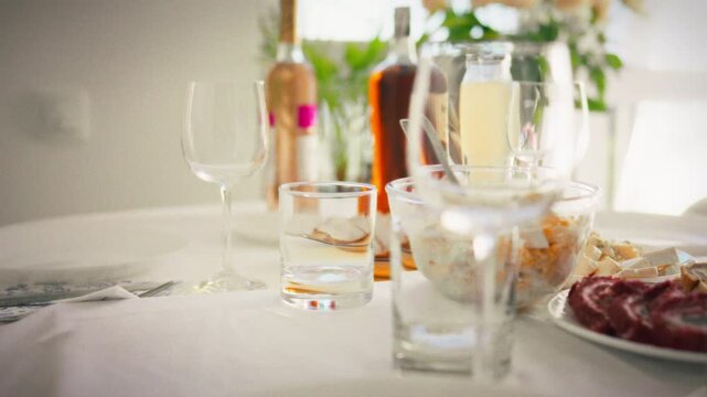 Elegant banquet-style buffet in bright daylight, medium shot gliding along white tablecloths with salads, canapes, meat skewers and sliced jamon, a catering spread ready for hungry guests