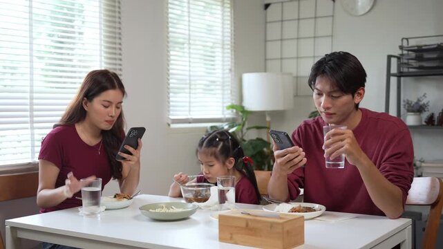 Phubbing parents ignoring their daughter while using smartphones during a family meal at home