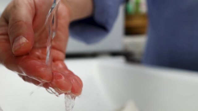 Hand Under Running Water in Soft Indoor Light Emphasizing Wasteful Water Use