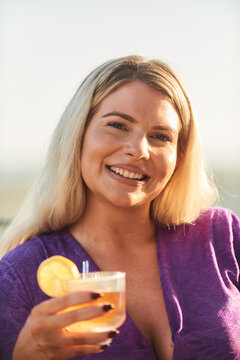 Smiling Blonde Woman Enjoying A Lemon Cocktail Outdoors During Summer Sunset Portrait