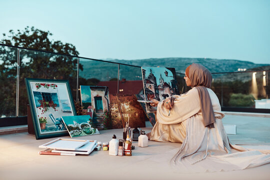Muslim Woman Painter In Hijab Creating Landscape Paintings On Rooftop At Dusk