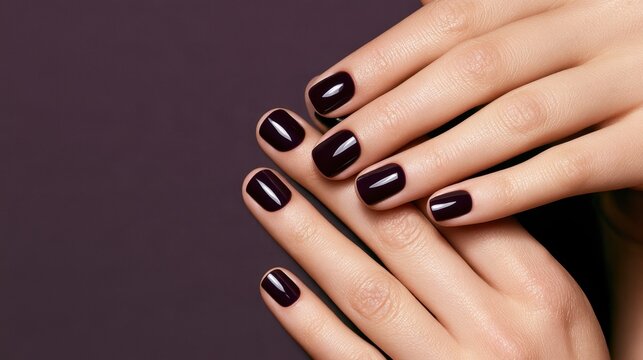Glossy deep plum manicure on feminine hands against a muted purple background
