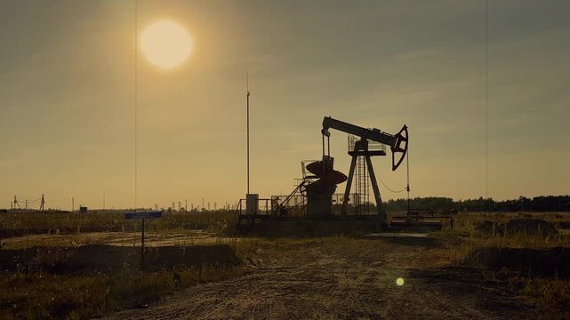 Oil extraction in oil field on evening sunset. Extraction of petroleum in night. Crude Oil Production. Crude pump jack working on oil field. Crude Pumpjack on sunrise. Industrial petroleum industry.