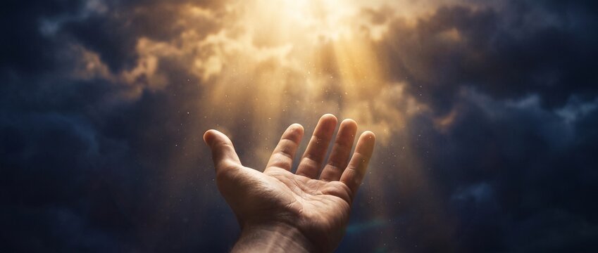 Mano de Jesucristo elev&aacute;ndose hacia rayos dorados divinos entre nubes de tormenta &mdash; concepto de salvaci&oacute;n y fe cristiana que simboliza oraci&oacute;n, esperanza y bendici&oacute;n de Dios