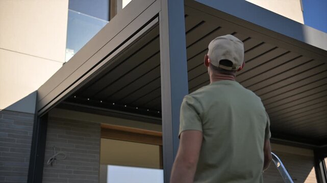 Worker looking up at a modern pergola beside a house
