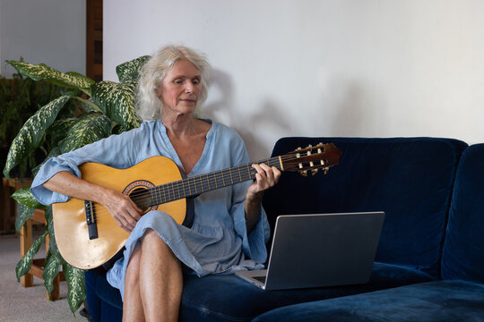 hobby, senior woman learns to play guitar with online lesson