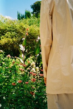 Person in Beige Jacket Standing Before a Summer Flower Garden