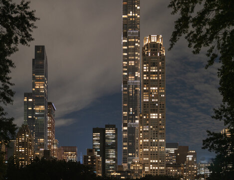 Midtown Manhattan skyscrapers glowing above Central Park at night