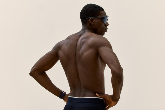 Muscular man poses against a plain background during a photoshoo