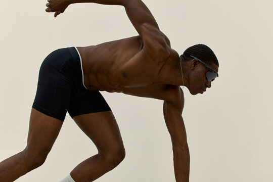 Runner prepares to sprint on a plain background