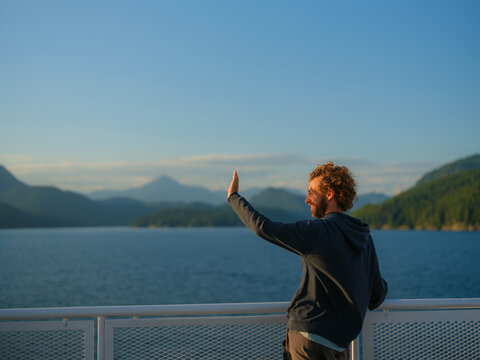 Man at the ferry deck raising his hand to block sunlight