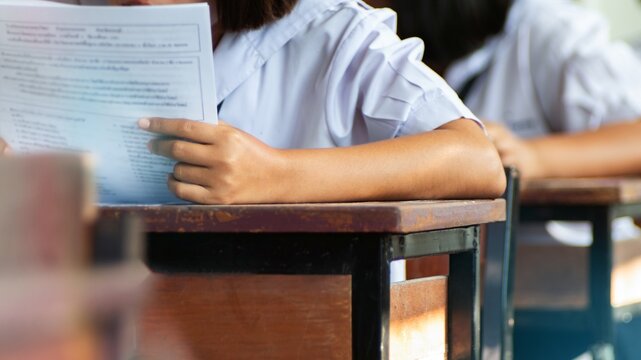 Close-up of Female Student Holding and Reading Exam Paper in Classroom
