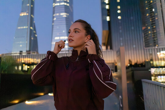 Young woman putting earphones preparing for urban run