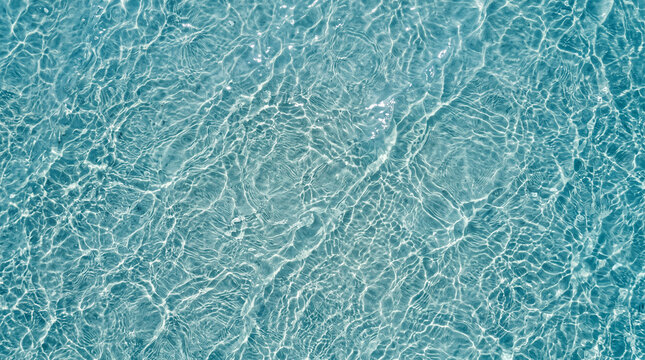 Top down angle of crystal clear ocean water texture under bright overhead sunlight