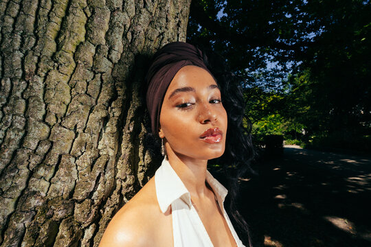Woman Leaning Against Park Tree