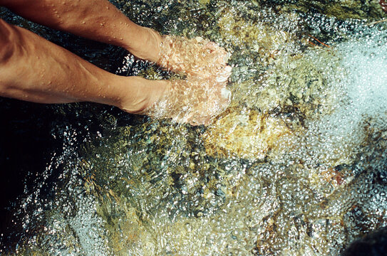 Person cooling feet in a clear mountain stream