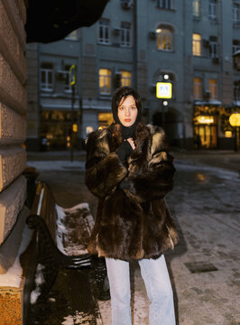 Model Stands on City Street Wearing a Fur Coat During Winter