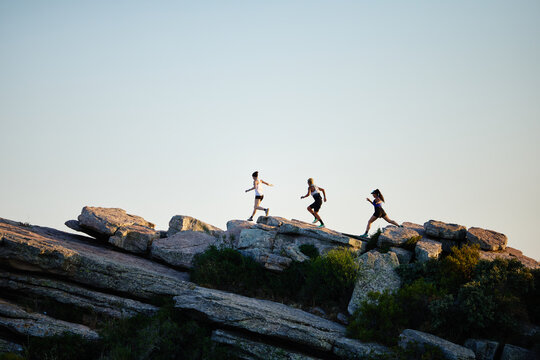 Friends running on rocky path during sunset