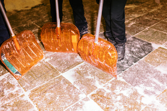 Workers Shovel Snow From a Stone Pathway During Winter