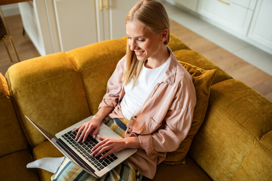 Smiling woman typing on a laptop at home