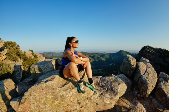Hiker resting on rocks during sunset in mountain area