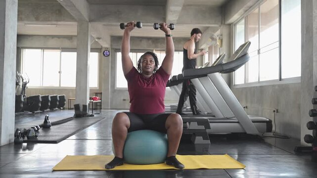 Female trainer assists a woman exercising with a stability ball on a gym mat, representing personal training, core fitness, balance, healthy lifestyle, coaching, motivation, and wellness.