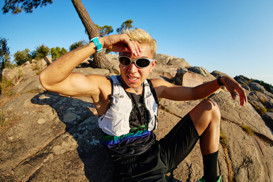 Runner resting on rocks with blue sky in the background