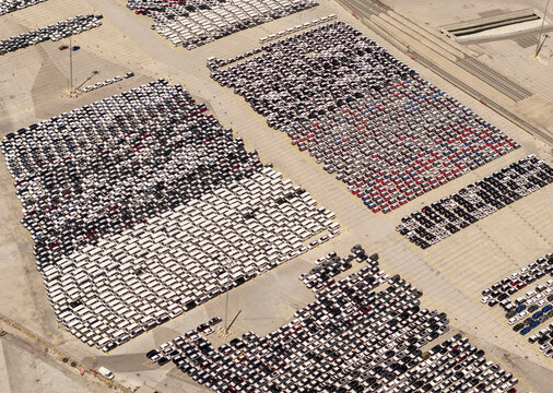 Hundreds of new cars parked in port terminal.