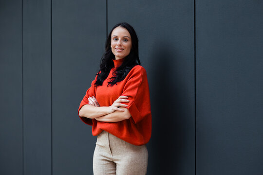 Professional woman standing with arms crossed, smiling, portraying confidence, leadership, and success in a modern business environment