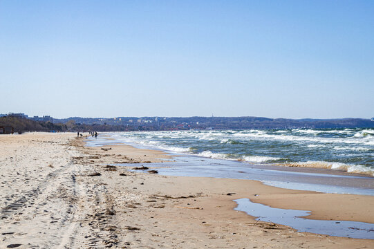 Baltic Sea beach in Gdańsk, Poland with sandy shore and waves under a clear blue sky