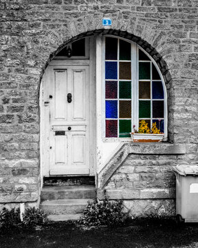 Traditional stone house entrance in Brittany France with stained glass arched window and selective color