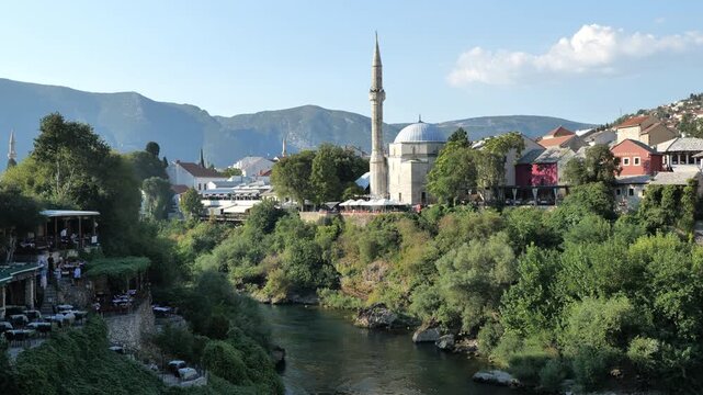 Aerial view of the historic Old Bridge (Stari Most) surrounded by traditional stone buildings, historic towers, and red-roofed houses in the old town at dusk in Mostar, Bosnia and Herzegovina