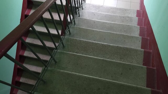Interior view of concrete stairs and metal handrails in an older apartment building, illustrating everyday residential architecture, shared housing infrastructure, property maintenance and building ac
