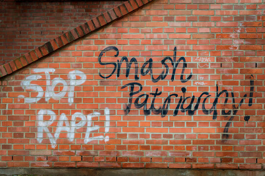 Feminist graffiti on a red brick wall reading "Stop Rape" and "Smash Patriarchy" in Brno, Czechia