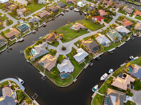 Sunset aerial view of Punta Gorda wealthy neighborhood. Expensive residential homes along canals reflect warm evening sky.