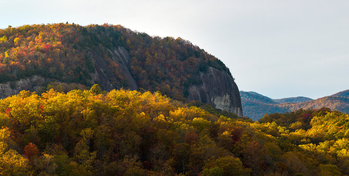Sunset autumn view of Looking Glass Rock surrounded with Appalachian forest hills. Lush woods with golden trees in colorful fall season.